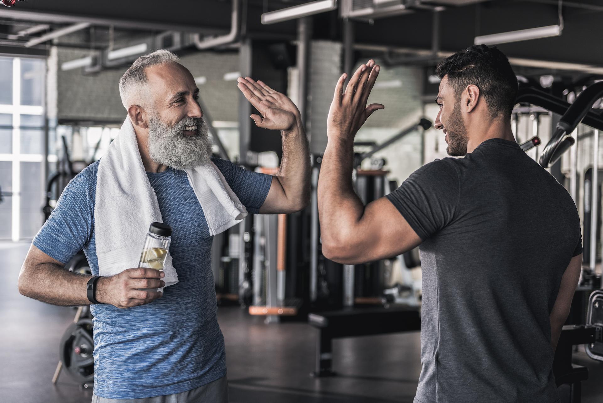Male Personal trainer congratulates elderly student with high five